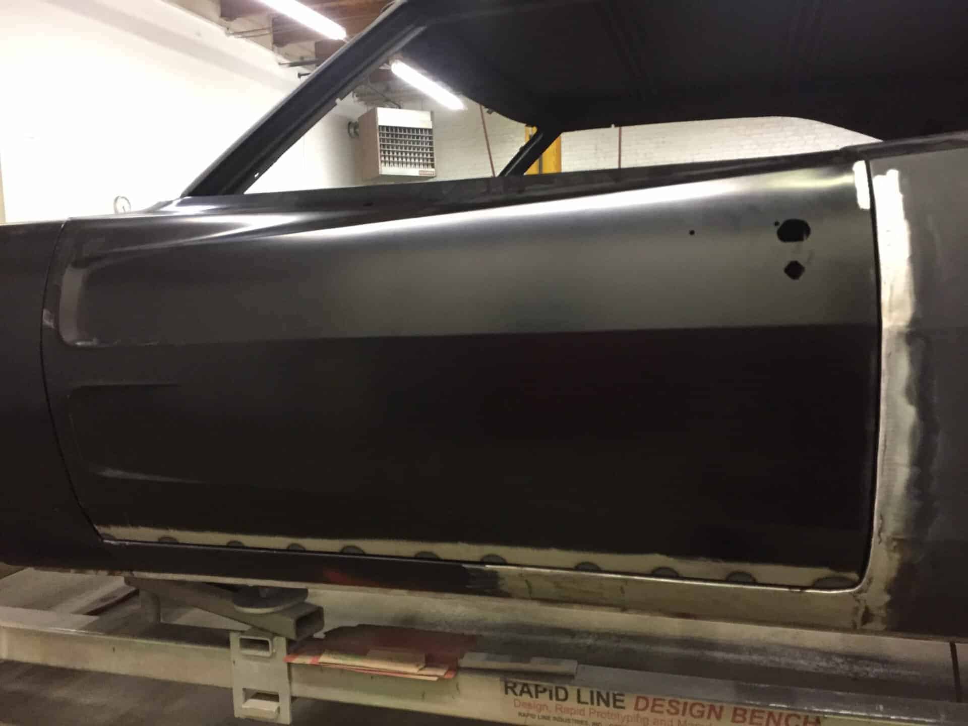 Black 1968 Dodge Charger door panel with primer and bodywork.
