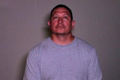 Man in gray T-shirt looking at camera against plain background.