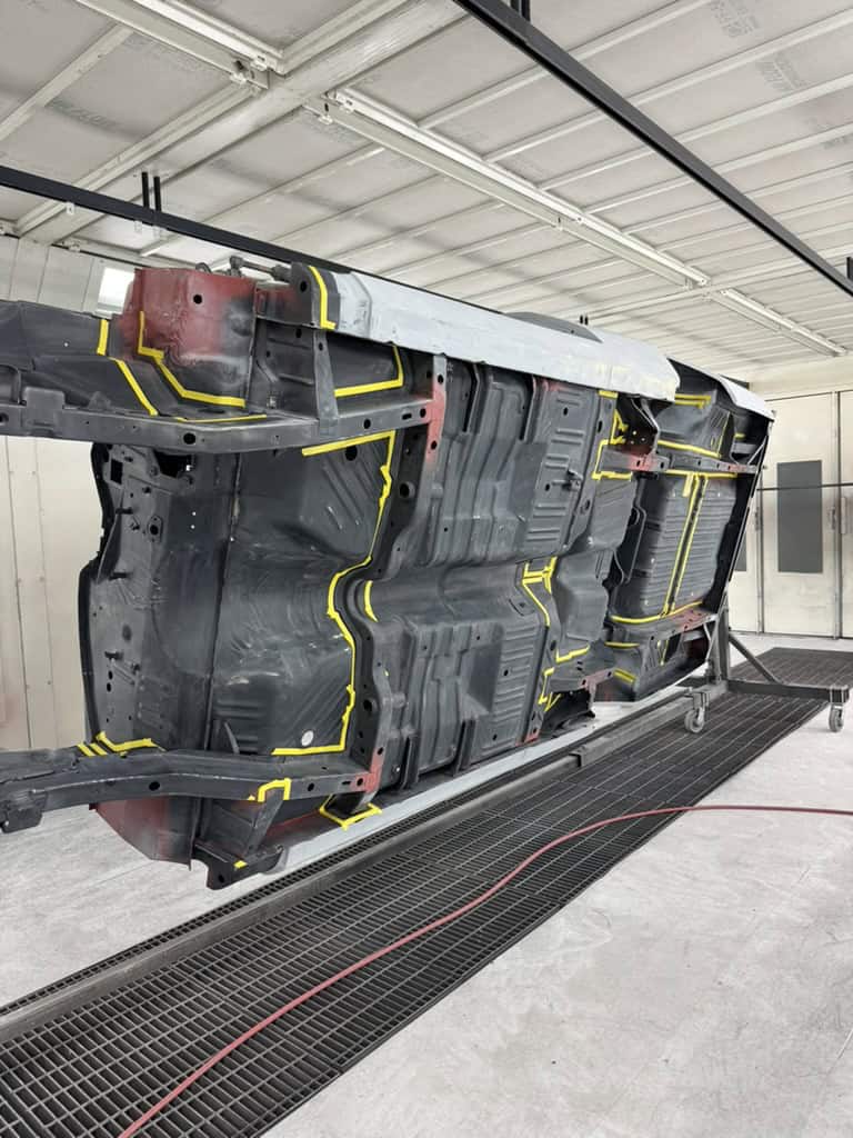 Car chassis upside down during restoration process at All Speed Customs.
