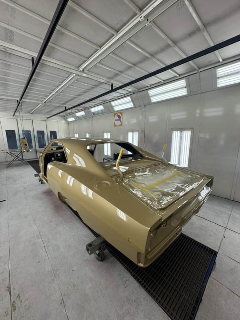 Gold car body in a paint booth at All Speed Customs workshop.