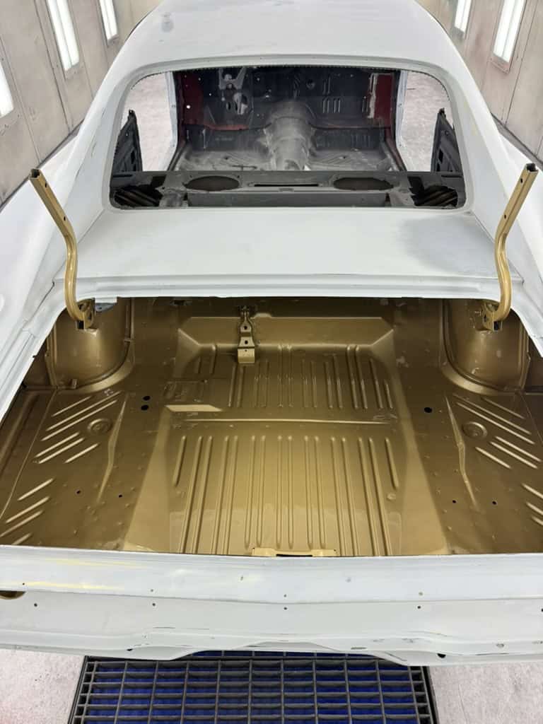 Restored classic car interior with gold floor and white exterior.