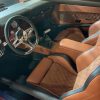 Driver interior of classic muscle car with custom tan and quilted leather seats and vintage dashboard.
