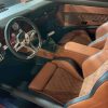 Driver interior of classic muscle car with custom tan and quilted leather seats and vintage dashboard.
