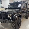 Black off-road custom Land Rover Defender at All Speed Customs, featuring rugged tires and aftermarket protection.