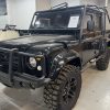 Black off-road custom Land Rover Defender at All Speed Customs, featuring rugged tires and aftermarket protection.