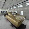 Gold car body in a paint booth at All Speed Customs workshop.