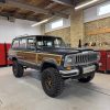 Modified Jeep Wagoneer with off-road tires in workshop.
