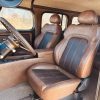 Interior of vintage vehicle with brown leather seats and dashboard.