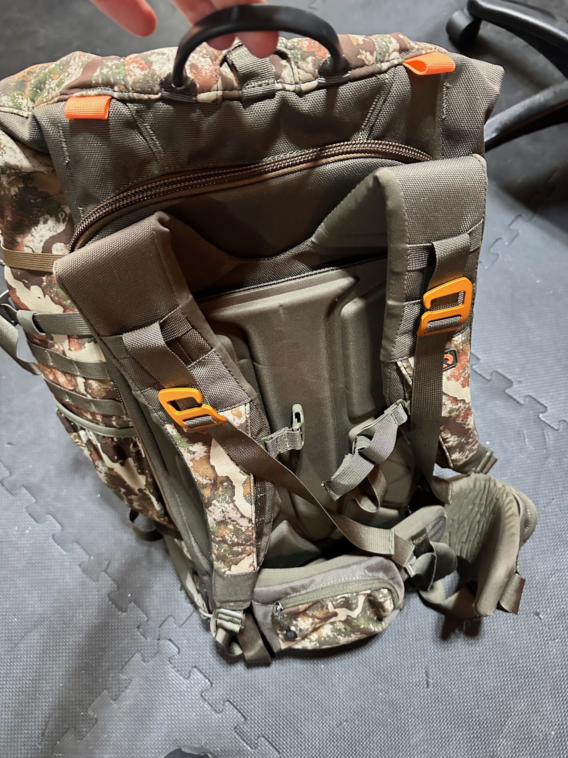 Back of First Lite Transfer Pack showing padded adjustable shoulder harness, hip belt, and treestand carry straps