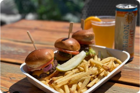 Delicious sliders with fries and drinks on a rooftop table at Attwood's Kitchen & Drink.