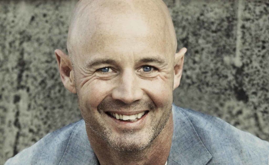 Glimlachende man met een pas geschoren hoofd en lichte stoppels