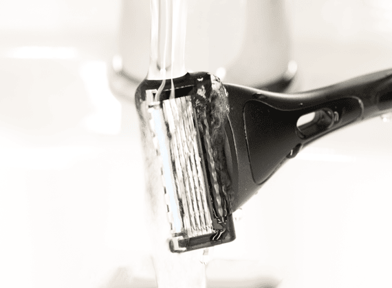 Een scheermes met vijf mesjes dat onder stromend water wordt afgespoeld