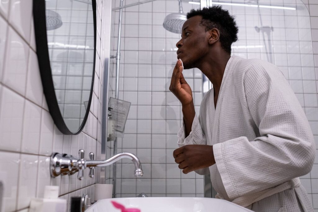 Een man in een badjas die voor het scheren zijn baardgroei in de spiegel bekijkt