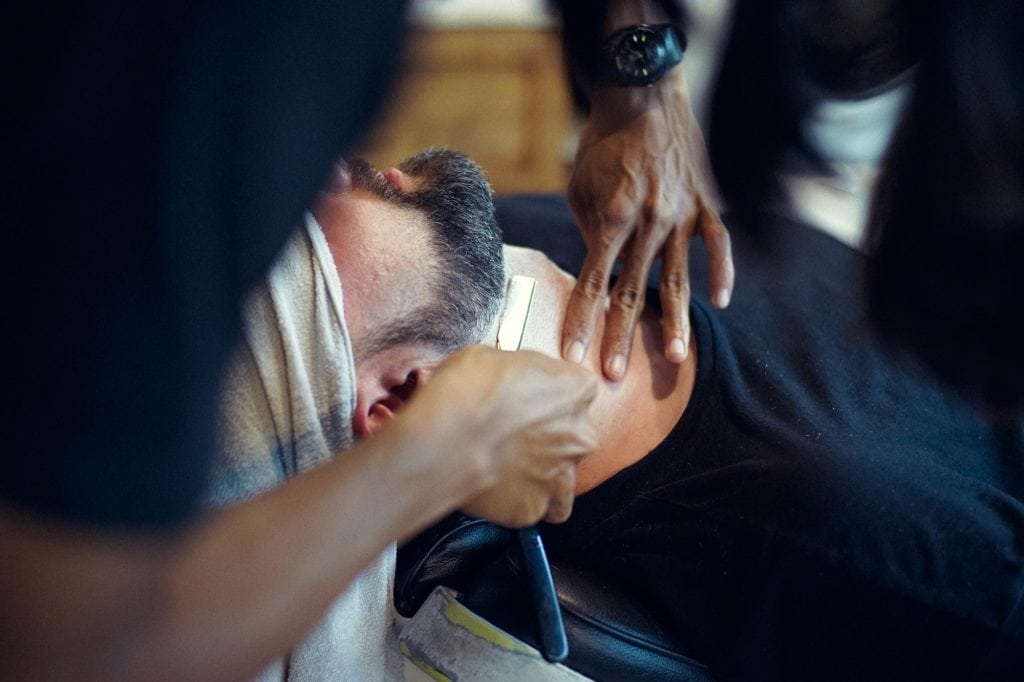 Barber shaving a man's neck with a straight razor