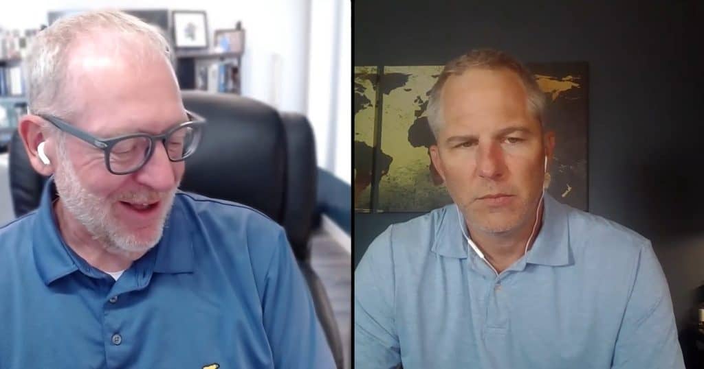 Two men in a podcast interview, one smiling, one serious, in a professional setting.
