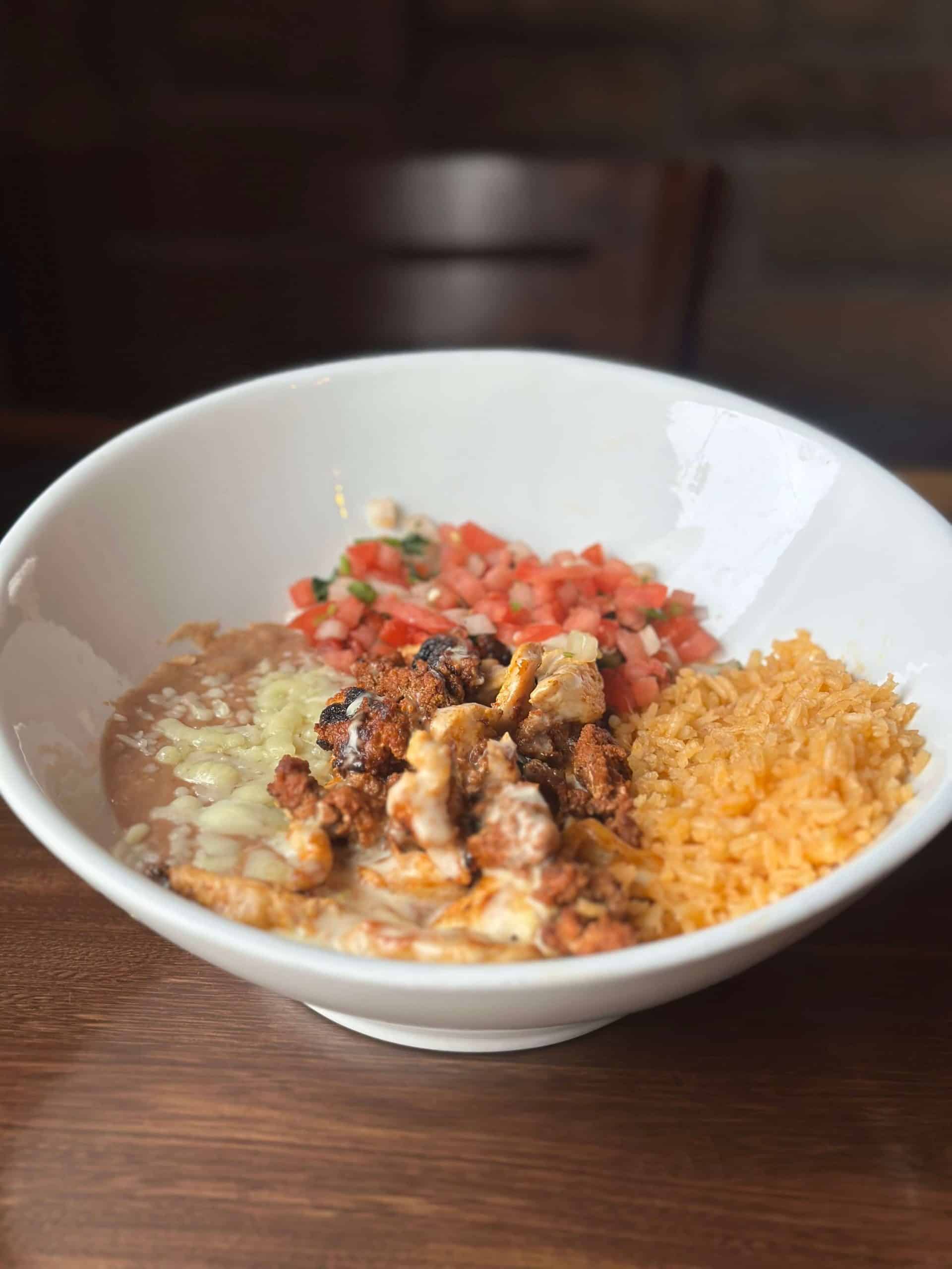 Delicious Mexican rice served with fresh pico de gallo, seasoned meat, and melted cheese in a white.