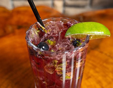 Refreshing berry lime cocktail with fresh blueberries and a lime wedge.
