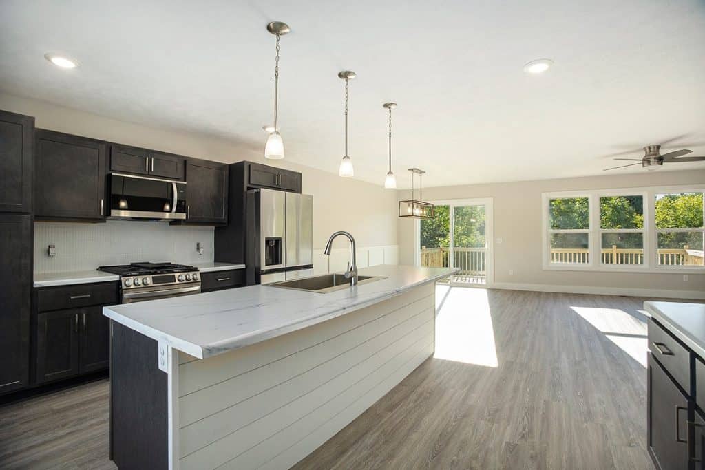 Spacious modern kitchen with island, black cabinets, and stainless steel appliances.