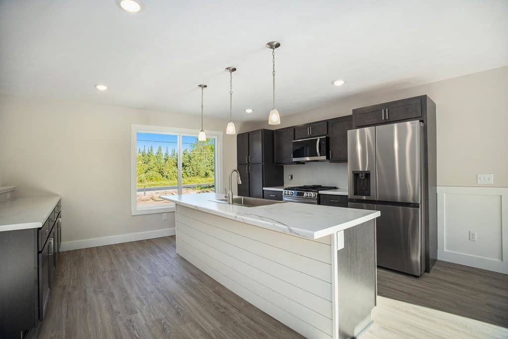 Contemporary kitchen with island, stainless steel appliances, and dark cabinets.