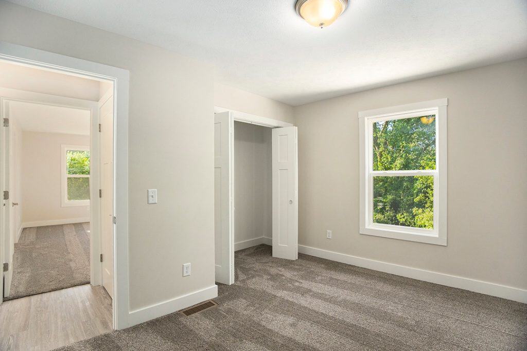 Bright bedroom with large window and neutral decor for modern living.