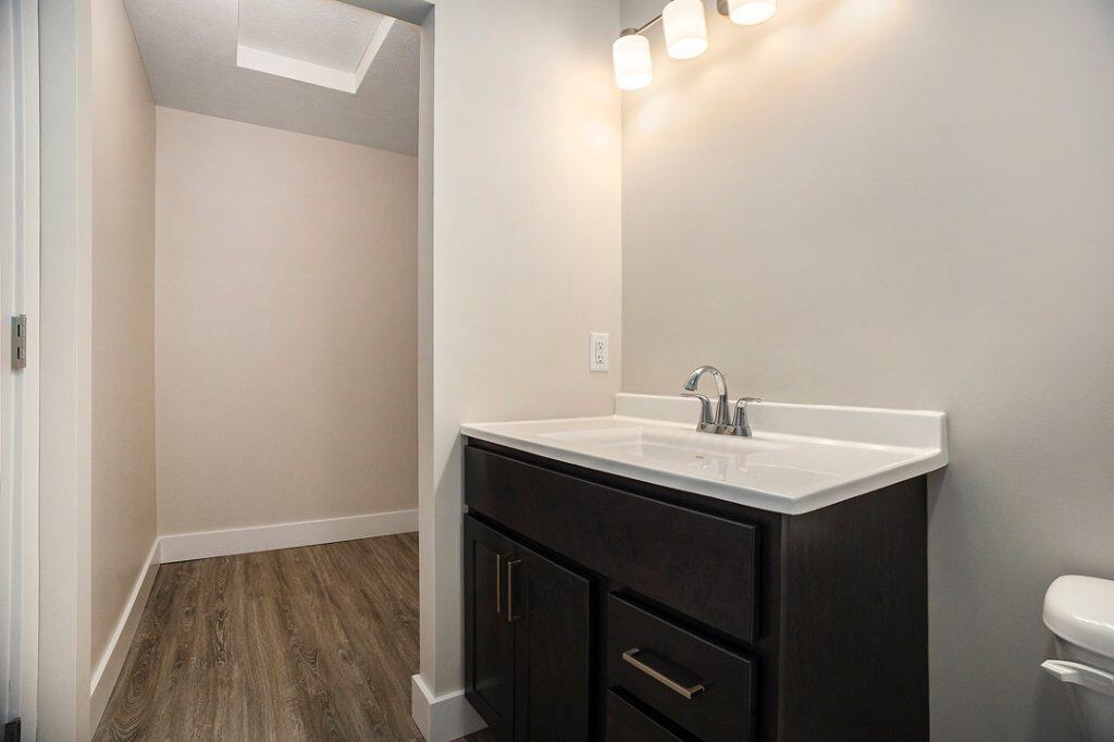 Contemporary bathroom with dark wood vanity and white sink.