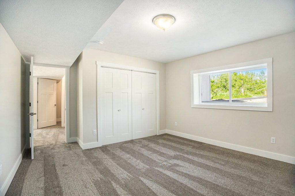 Bright and spacious bedroom with large window and neutral decor.
