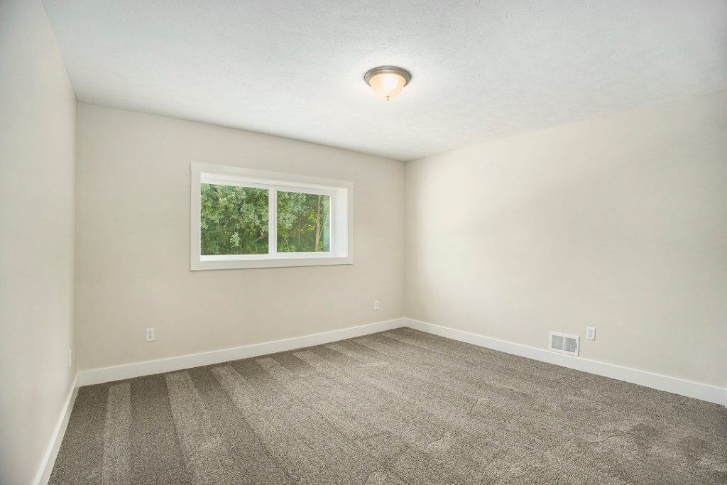 Empty bedroom with window and neutral walls in a new home.