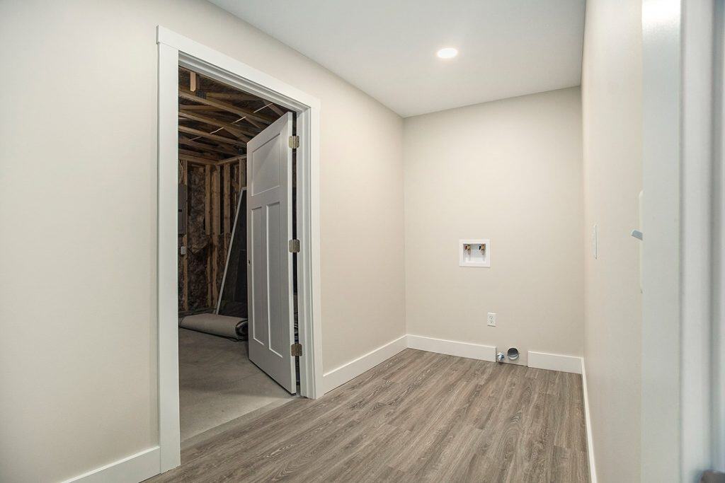 Empty room with white walls and wood flooring in a new home.