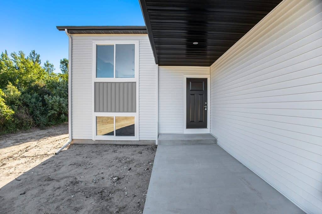 Contemporary house exterior with white siding and black door.