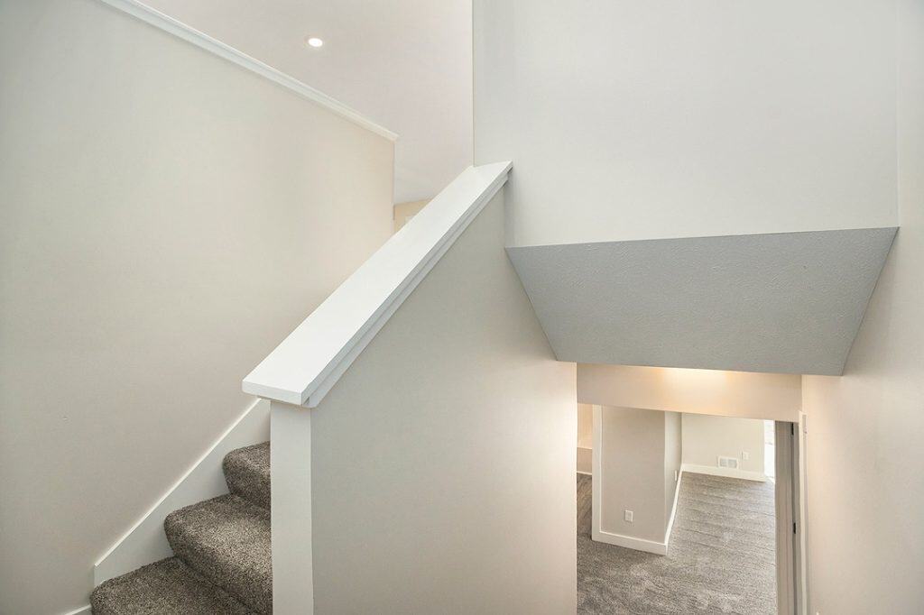 Contemporary staircase with carpeted steps and minimalist white walls.