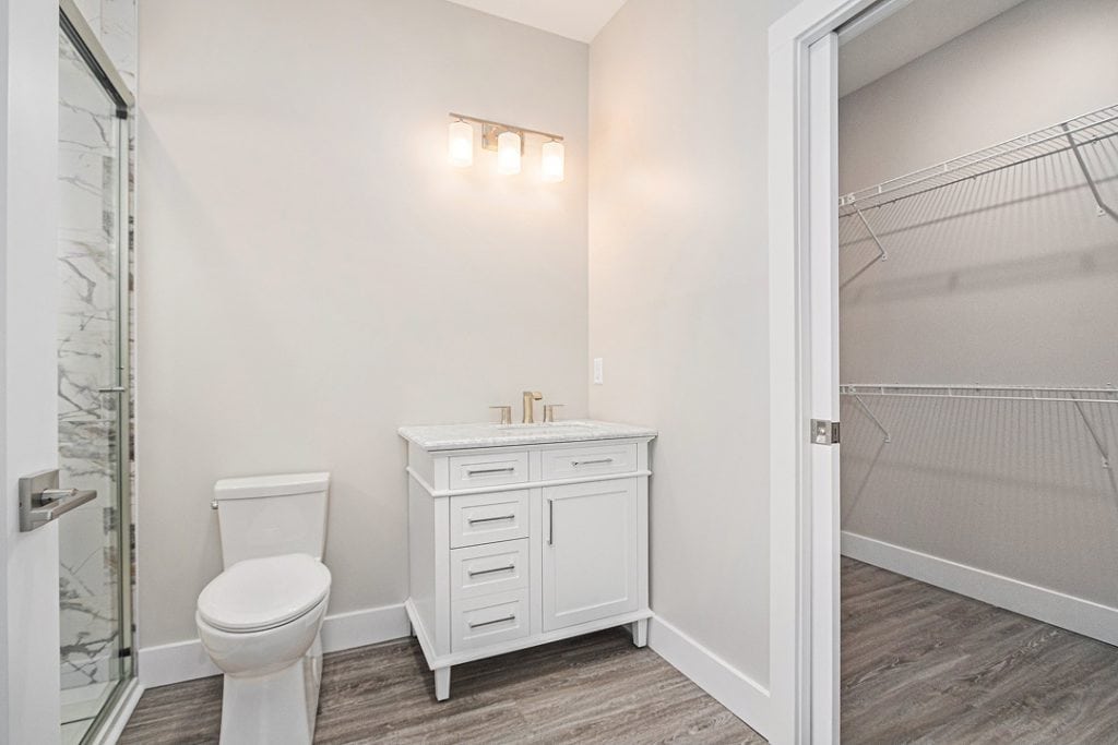 Bright modern bathroom with white vanity and walk-in closet.