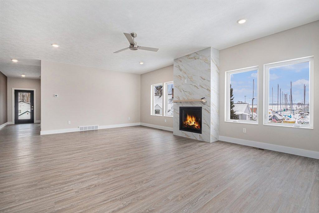 Spacious living room with fireplace and large windows overlooking marina.
