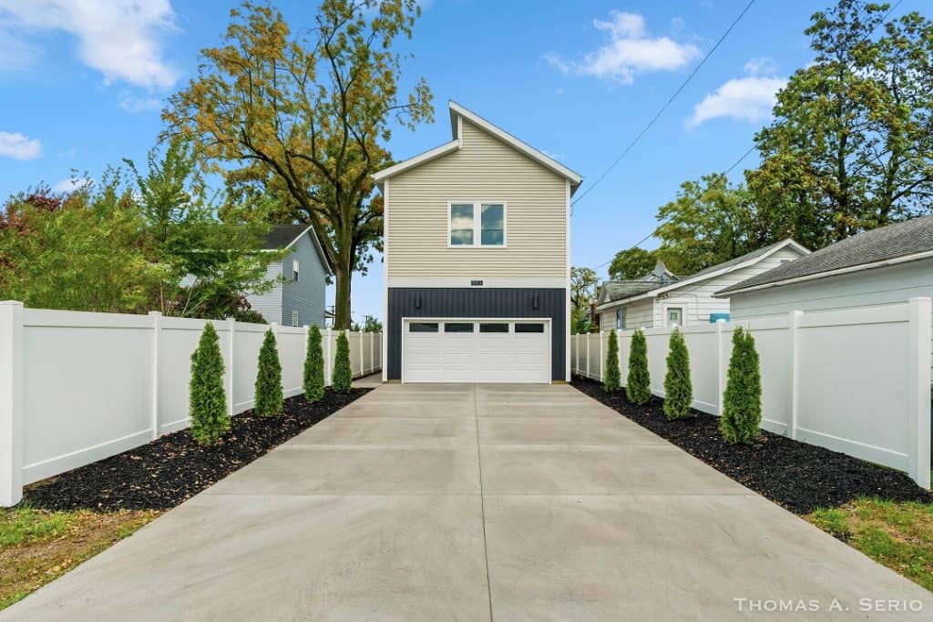 New two-story garage home with white fencing and landscaped yard.