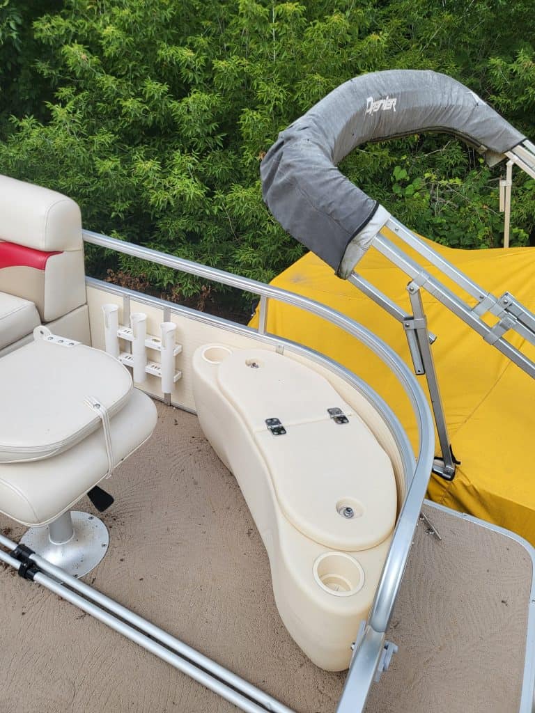 Pontoon boat with fishing and lounging features on water.