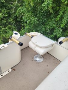 Boat deck with fishing seats and green foliage background.