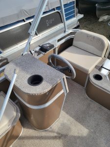 Pontoon boat interior with seating and steering console for lake fun and water recreation.