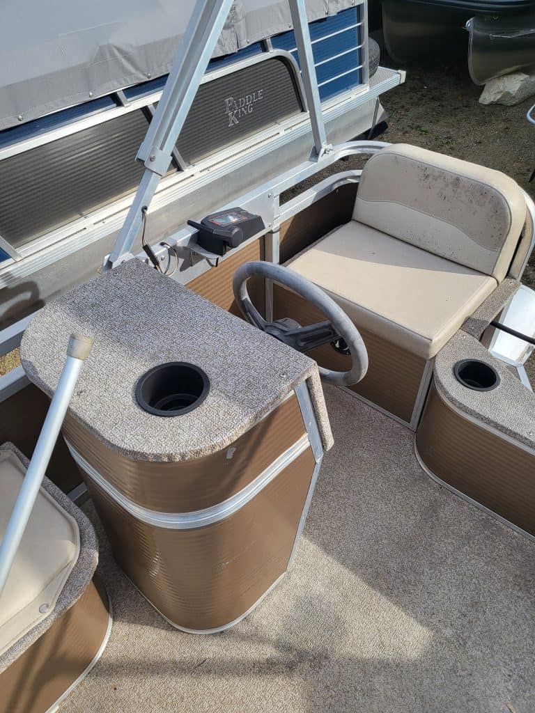 Pontoon boat interior with seating and steering console for lake fun and water recreation.