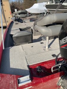 Used Bass Tracker 17 boat with seating and motor in boat yard.
