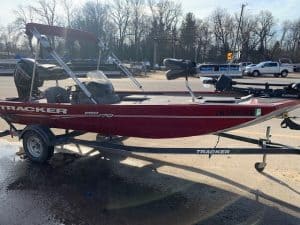 Red Bass Tracker 17 boat on trailer with fishing gear and outboard motor.