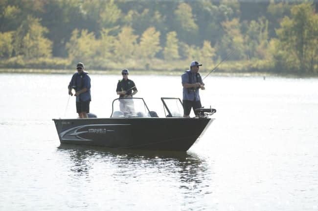 Three people fishing on a Starweld Flex 17 DC boat on a lake.
