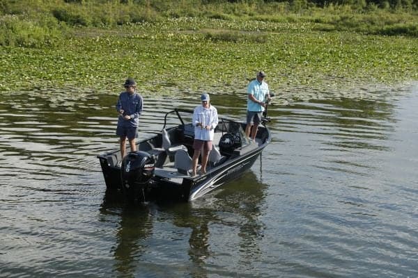Fishing boat with three people on a lake, outdoor water activity.