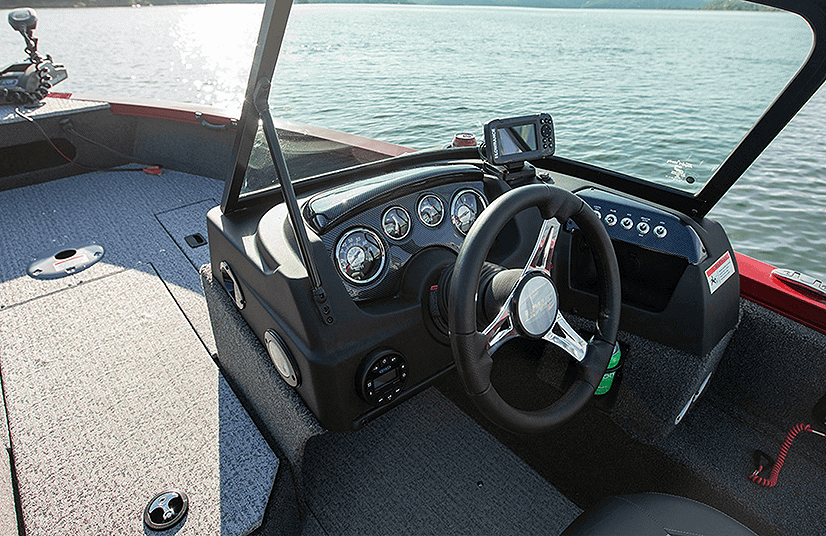 Boat cockpit with steering wheel and gauges on a lake.