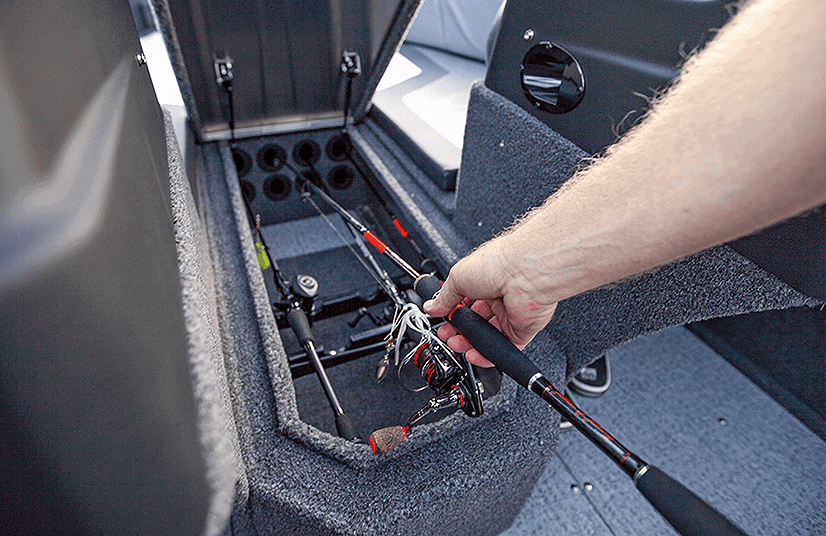 Person accessing storage compartment with fishing gear in Lowe Boats FM1800.