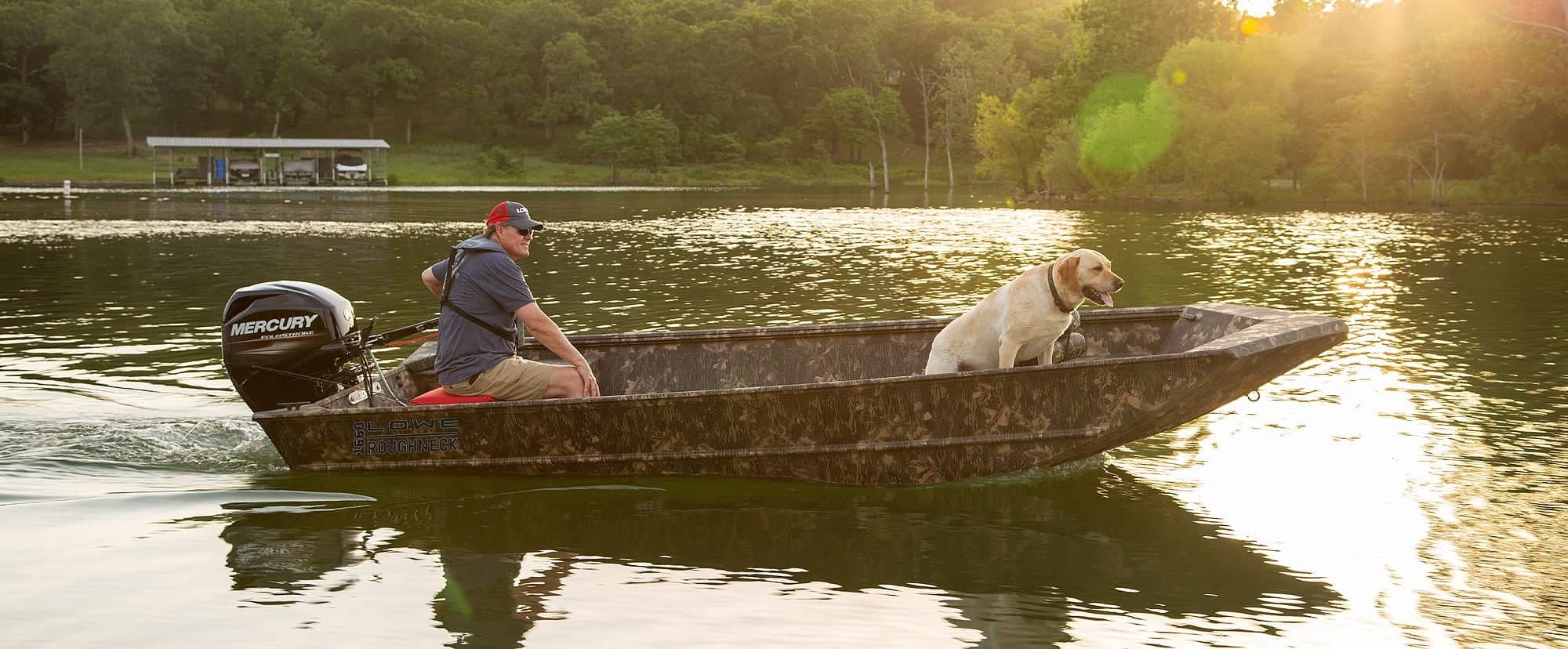 Man and dog enjoying a boat ride on a calm lake at sunset.