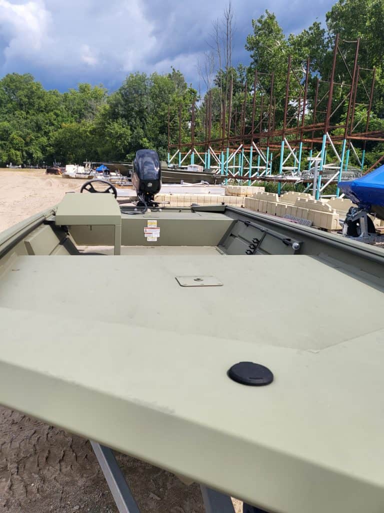 Lowe Boats RX1760 boat on sandy shore with trees and construction in background.