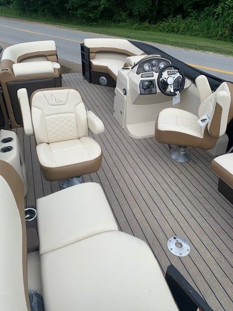 Luxury pontoon boat interior with beige seating and steering console.