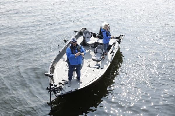 Fishing boat with two people on the water, equipped with modern gear.
