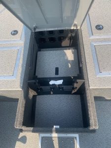 Boat storage compartment with access panel and multiple circular openings.