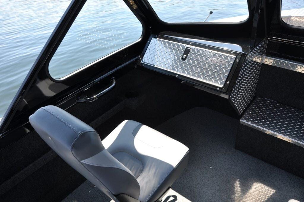 Boat interior with captain's chair and storage compartment.