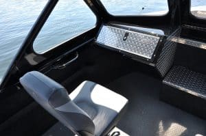 Boat interior with captain's chair and storage compartment.